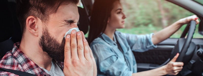 Man in car sneezing