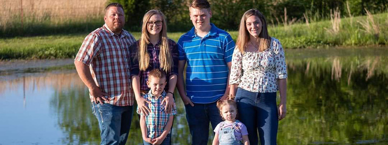 The Sanders family posing standing by a pond