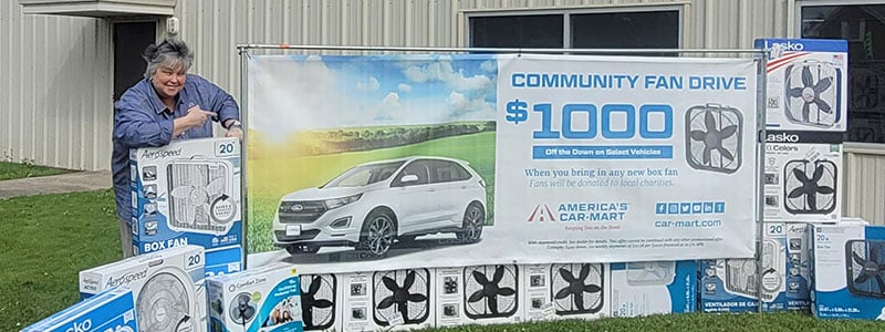 Stacy Barrett, General Manager, America’s Car-Mart of Tullahoma, Tenn with some of the box fans her dealership has collected for our Community Fan Drive
