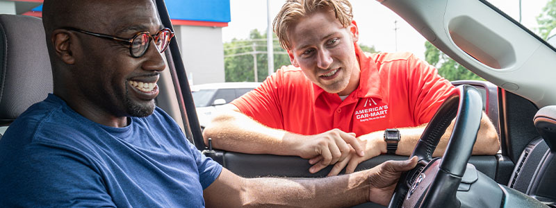Man sitting in car with a sales associate looking through the driver window