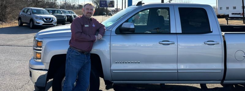 Jesse Rob General Manager at America's Car-Mart of Bowling Green Kentucky standing by a Chevy Silverado truck.